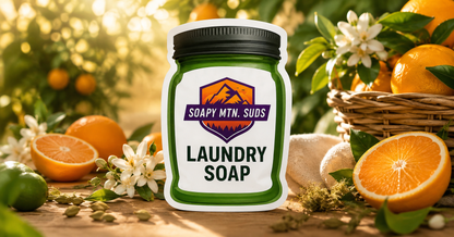 Orange Grove Laundry Soap by Soapy Mtn Suds displayed in a luxury citrus grove with fresh oranges, orange blossoms, lime, and cardamom, inspired by Mediterranean citrus and premium designer fragrances.
