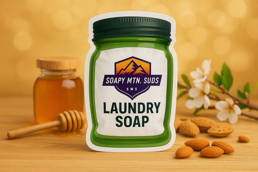 Soapy Mtn Suds Honey Almond Laundry Soap pouch with honey jar, almonds, and white blossoms on a golden background.
